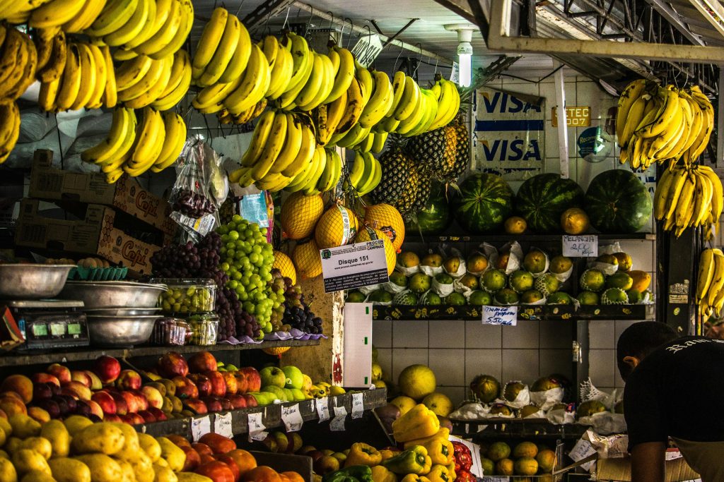 Vibrant fruit stall in an urban market featuring bananas, apples, and more.